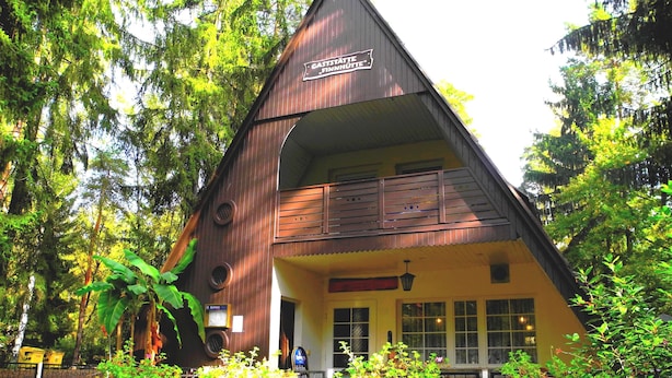 Una cabaña de madera con un letrero que dice 'GASTSTÄTTE FINNHÜTTE'.