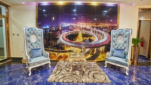 A luxurious lobby with two ornate armchairs, a central table, and a large cityscape mural on the wall. - Corinthia Villa Hotel (Abuja)