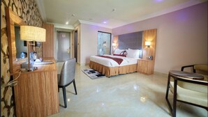 A hotel room with a bed, desk, chair, and a small table. - Corinthia Villa Hotel (Abuja)