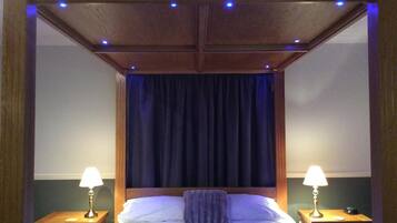 A bedroom with a large bed, dark curtains, and two bedside lamps.