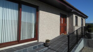 A building with a large window, a door, and a small balcony. - Hillview Park (Beauly)