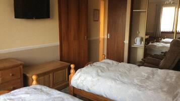 Una habitación de hotel con dos camas, muebles de madera, un televisor en la pared y un espejo.