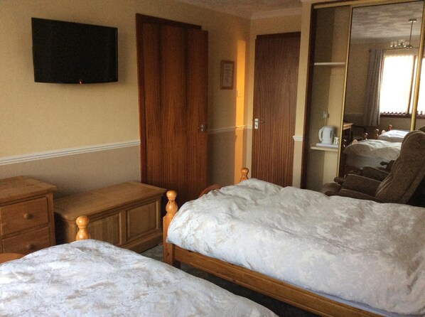 Una habitación de hotel con dos camas, muebles de madera, un televisor en la pared y un espejo.