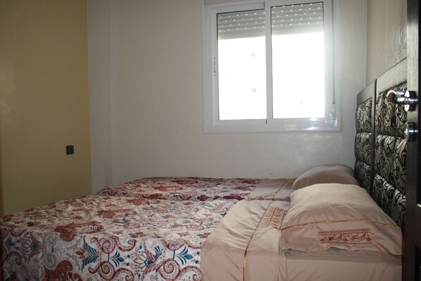 A bedroom with a bed, a window, and a patterned headboard.
