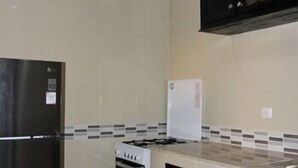 Una cocina con refrigerador, estufa y alacenas.
