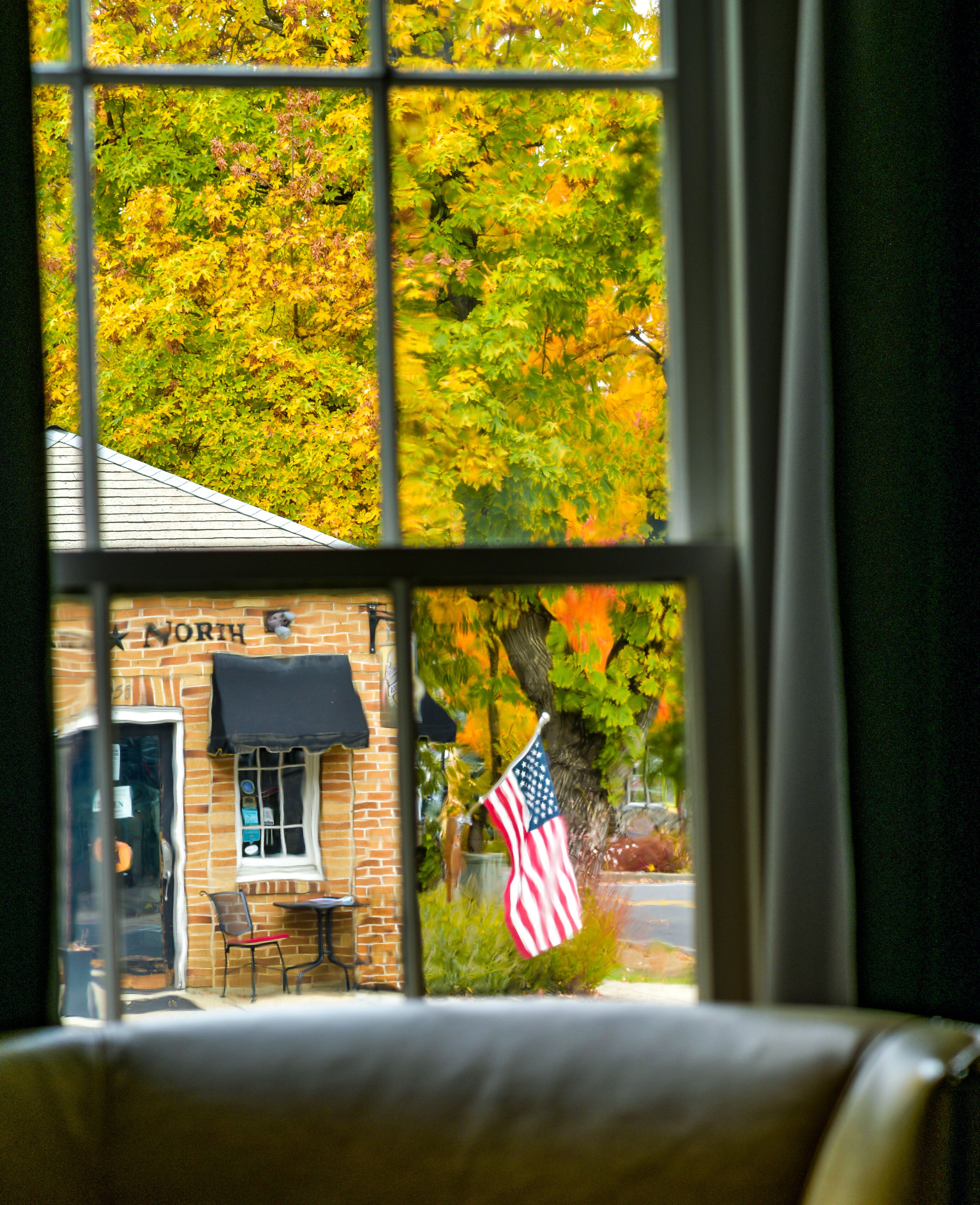 Blick durch ein Fenster auf ein Backsteingebäude mit der Aufschrift „NORTH“ und eine amerikanische Flagge davor.