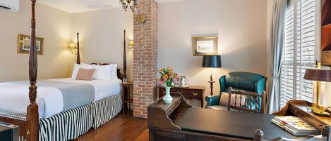A hotel room with a four-poster bed, a dining table, and a brick accent wall.