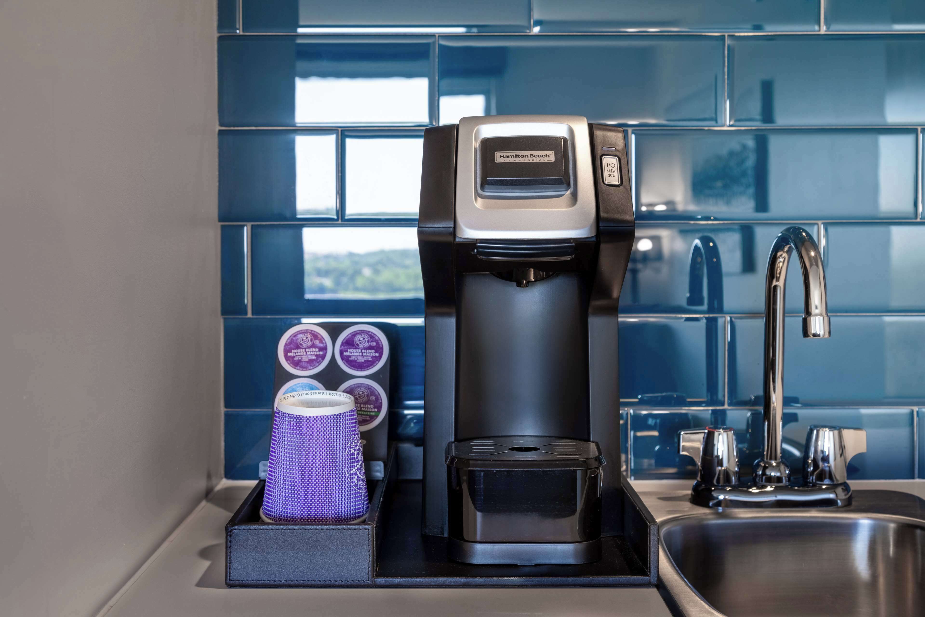 Une machine à café dotée d’un réservoir d’eau et d’un compartiment pour les dosettes de café, posée sur un plan de travail de cuisine.