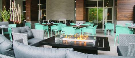 An outdoor seating area with a fire feature, green chairs, and a modern design.