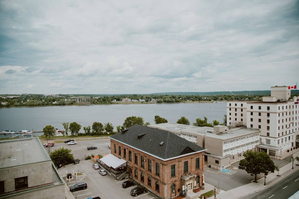 Une vue sur la ville, prise depuis la rive, avec un imposant bâtiment en briques et un bâtiment moderne de couleur blanche.