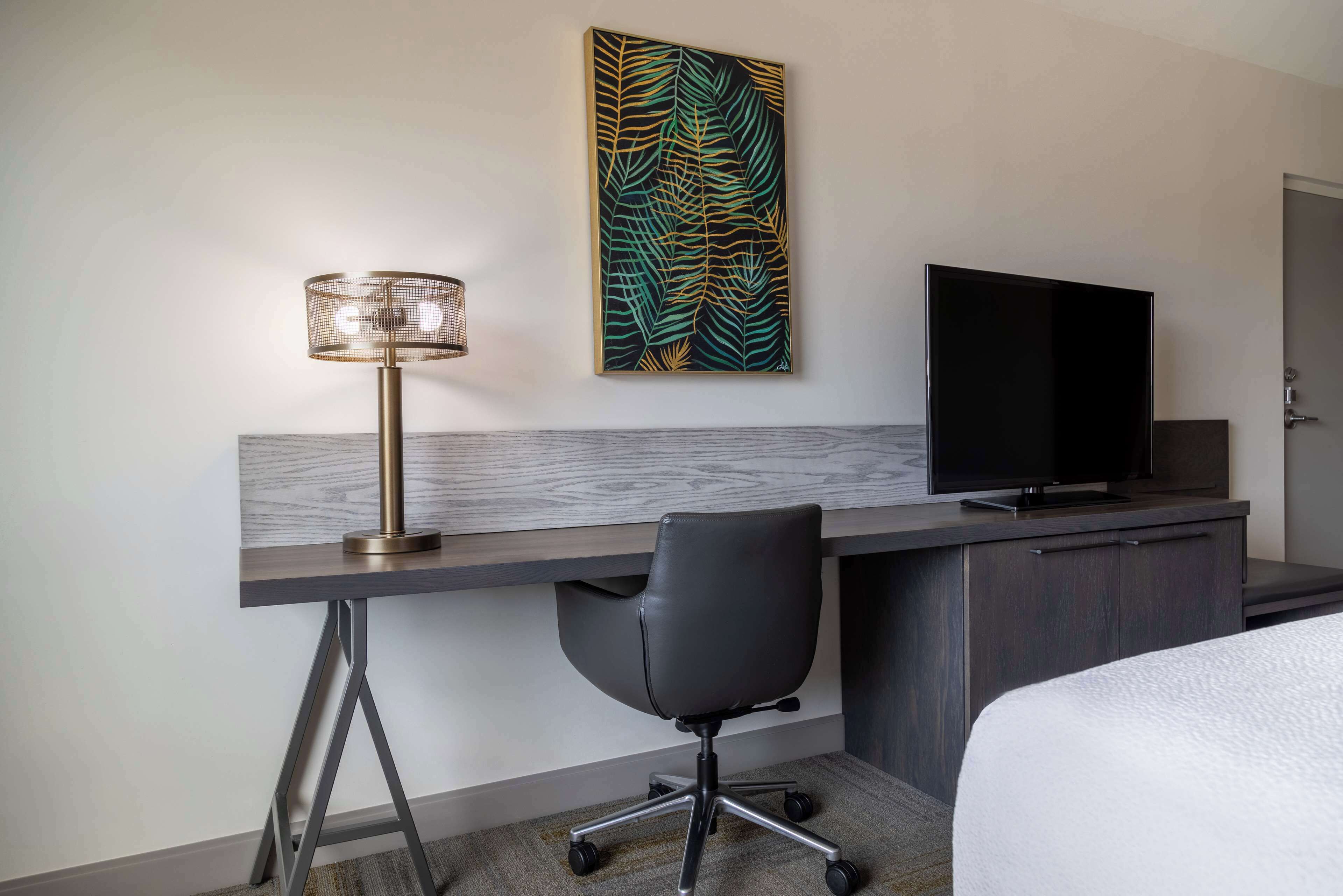 Una habitación de hotel con escritorio, televisor, silla y cama.