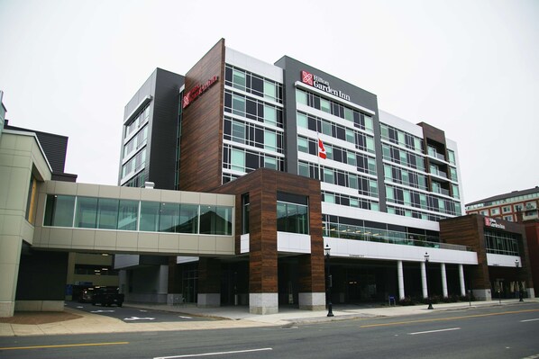 A modern hotel with a prominent Hilton Garden Inn sign, large glass windows, and a covered entrance area.