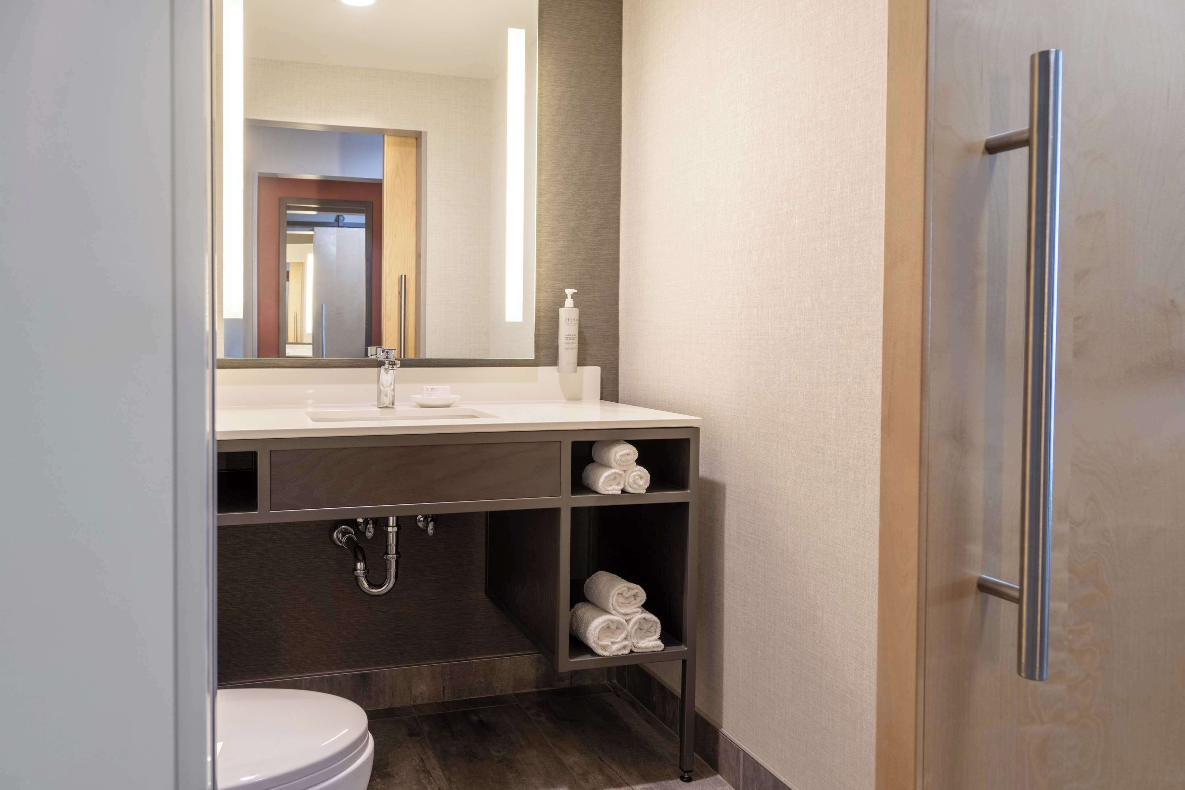 A modern bathroom with a white sink, a mirror, and a towel rack.