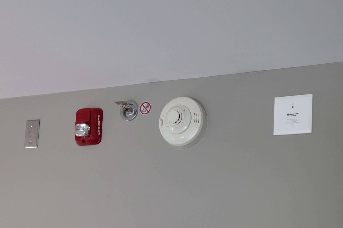 Un détecteur d’incendie fixé au mur, un détecteur de fumée, un interrupteur et un panneau.