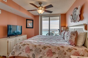 A bedroom with a bed, a television, a ceiling fan, and a view of the ocean. - Bahama Sands by Condo-World (North Myrtle Beach)