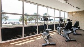 Une salle de sport avec de grandes fenêtres donnant sur une plage.