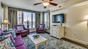 Un salon comprenant un canapé, des fauteuils, une table basse, un téléviseur et un ventilateur de plafond.