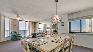 Ein geräumiger Essbereich mit einem großen Tisch, Stühlen, einem Deckenventilator und einer Chandelier.