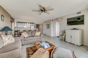 A spacious living room with a sofa, armchairs, a coffee table, and a television.