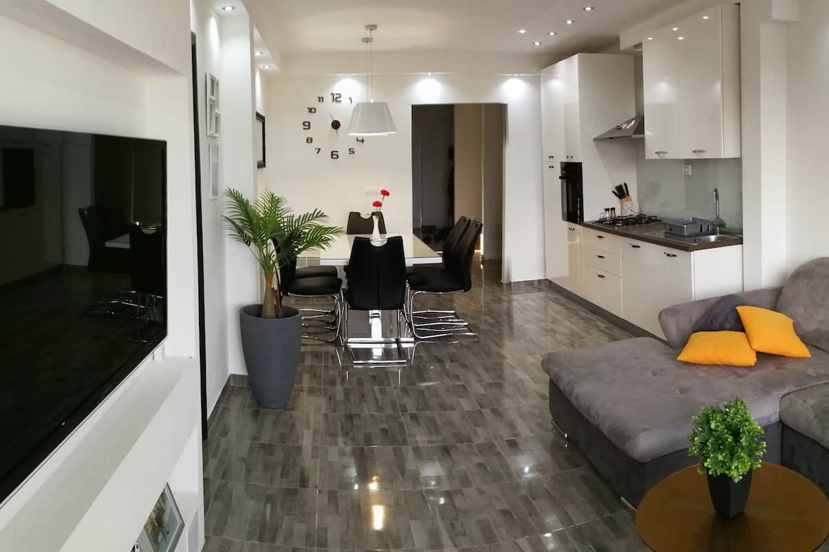 Een moderne woonkamer met een grijze bank, een salontafel, en een eethoek met een tafel en stoelen.