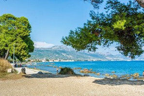Eine Küstenlandschaft mit freiem Blick auf das Meer, felsigem Ufer und Bergen in der Ferne.