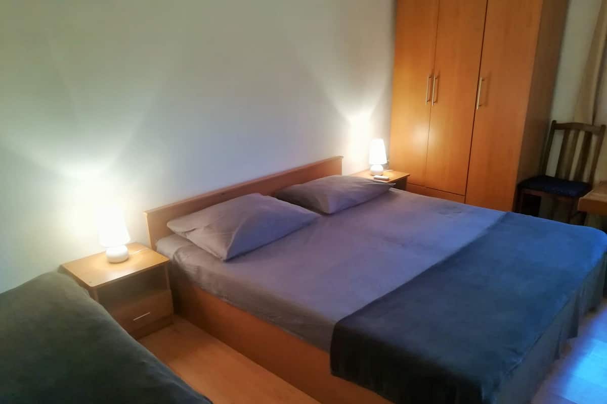 Een slaapkamer met een bed, twee nachtkastjes, een kledingkast en een bedtafel.