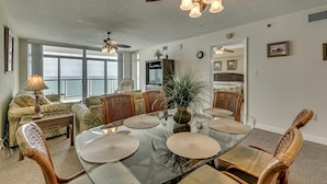 A dining area with a glass table, wicker chairs, and ceiling fans. - Blue Water Keyes by Condo-World (North Myrtle Beach)