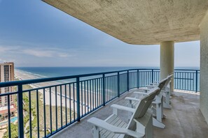 A balcony with white chairs overlooking a beach and ocean. - Brighton Tower by Condo-World (Myrtle Beach)