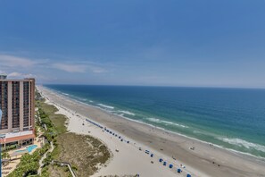 A beachfront hotel with a pool, beach umbrellas, and a view of the ocean. - Brighton Tower by Condo-World (Myrtle Beach)