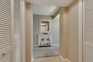 A hallway with a white console table, a mirror, and a door with a light fixture. - Brighton Tower by Condo-World (Myrtle Beach)