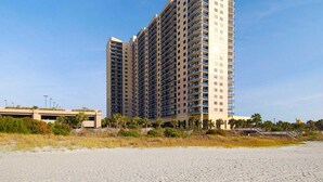 Ein Hochhaus-Hotel mit mehreren Balkonen in Strandnähe, mit einer Promenaden.