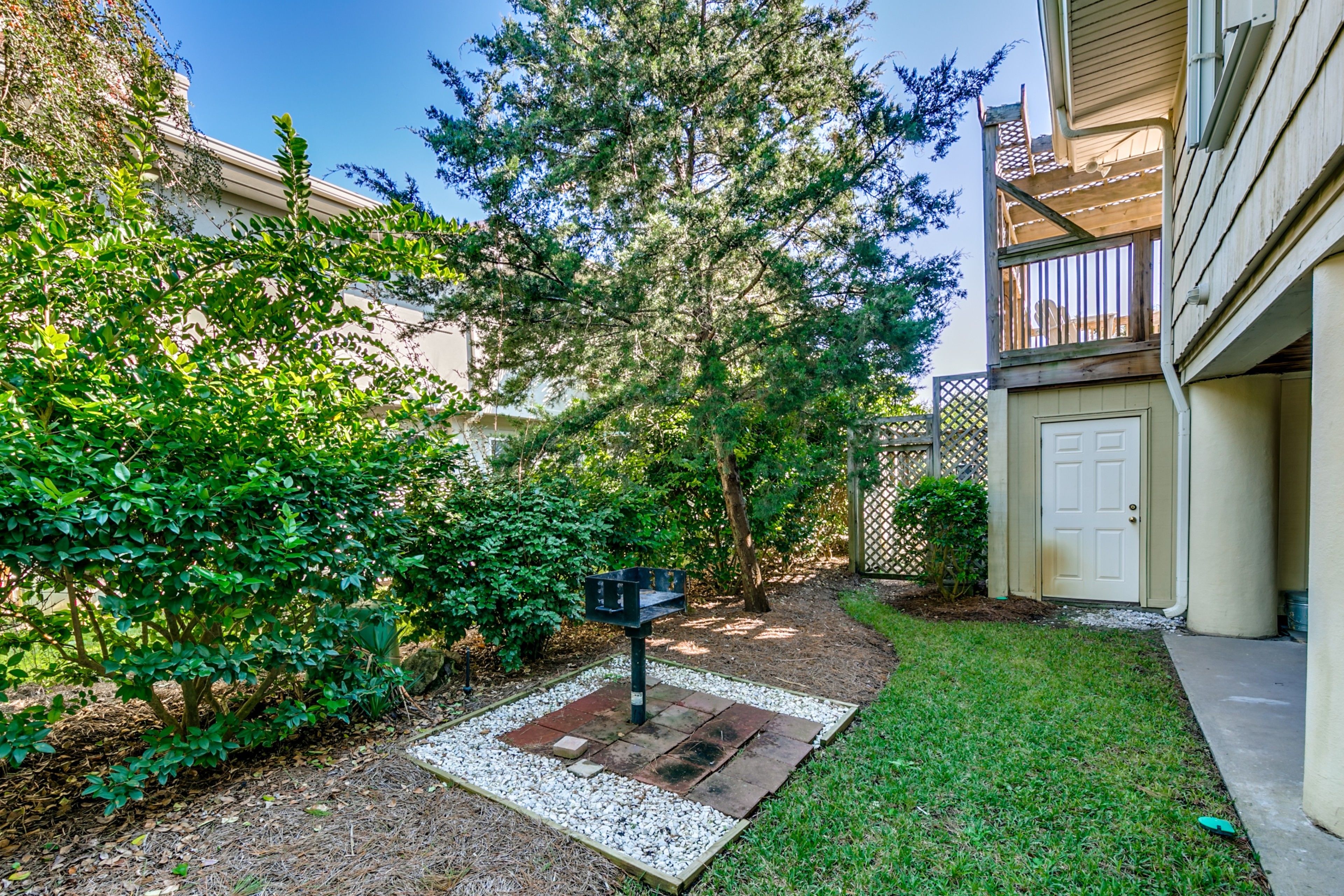 A residential backyard with a mailbox, a small garden area with gravel and grass, and a wooden deck.