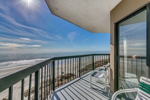 A balcony with a view of the beach and ocean.