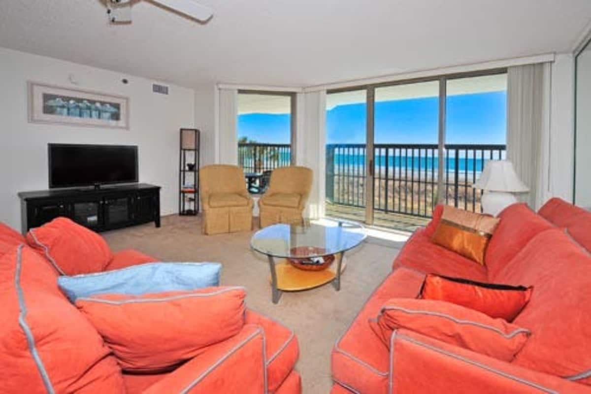 A living room with a large window, a flat-screen TV, and a sofa.