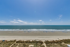 Een strand met een heldere lucht, zandstrand en een pad naar het water.