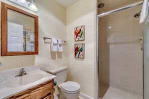 A bathroom with a wooden vanity, a white sink, a toilet, and a glass shower enclosure. - High C's by Condo-World (North Myrtle Beach)
