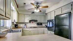 A kitchen with light wooden countertops, a stainless steel refrigerator, a microwave, and a ceiling fan. - High C's by Condo-World (North Myrtle Beach)