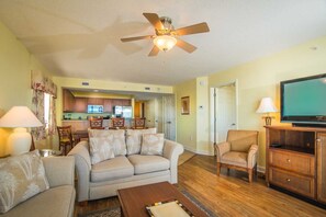 A living room with a sofa, armchairs, a coffee table, a TV, and a ceiling fan.