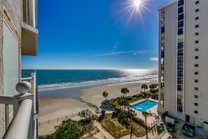 A high-rise hotel overlooking a beach with a swimming pool and palm trees. - Sea Watch Resort by Condo-World (Myrtle Beach)