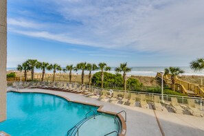 A pool area with a view of the beach and ocean.
