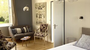 A bedroom with a large bed, a sofa, a chair, a small table, and a wall-mounted light fixture. - Hotel d'Angleterre (Etretat)