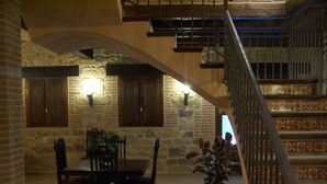 A rustic interior with a stone fireplace, wooden dining table, and a staircase with patterned tiles. - La Contrada (Arens de Lledo)