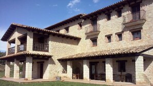 A stone building with multiple balconies and a covered patio area. - La Contrada (Arens de Lledo)