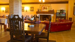 A cozy lobby with a fireplace, leather seating, and a wooden dining table. - La Contrada (Arens de Lledo)
