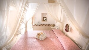 A bedroom with a bed, a bedside table, a mirror, and a hanging flower. - B&B Il Borgo (Poggiardo)