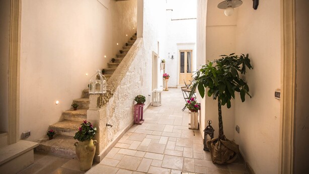 A narrow hallway with a stone staircase leading to a door at the end. - B&B Il Borgo (Poggiardo)