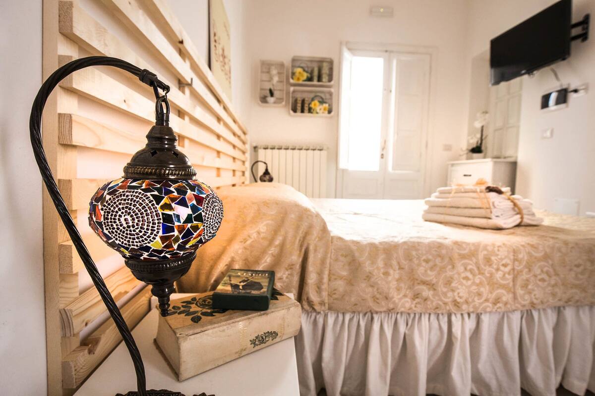 A room with a bed, a lamp, a radiator, and a door.