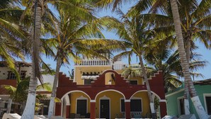 A building with a yellow facade, red arches, and a balcony.