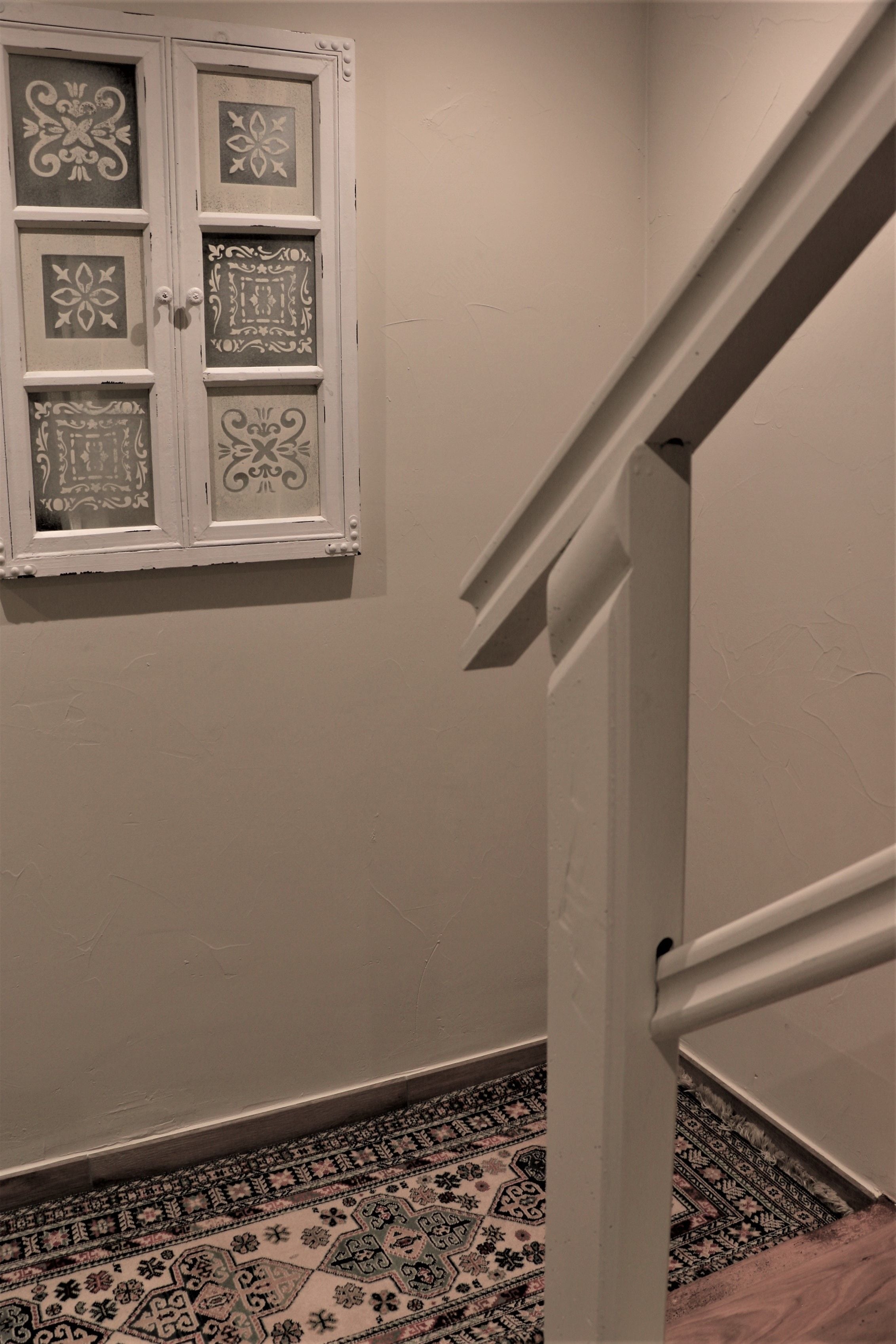 Eine Treppe mit weißer Handlauf und einem gemusterten Teppich am Fuß.