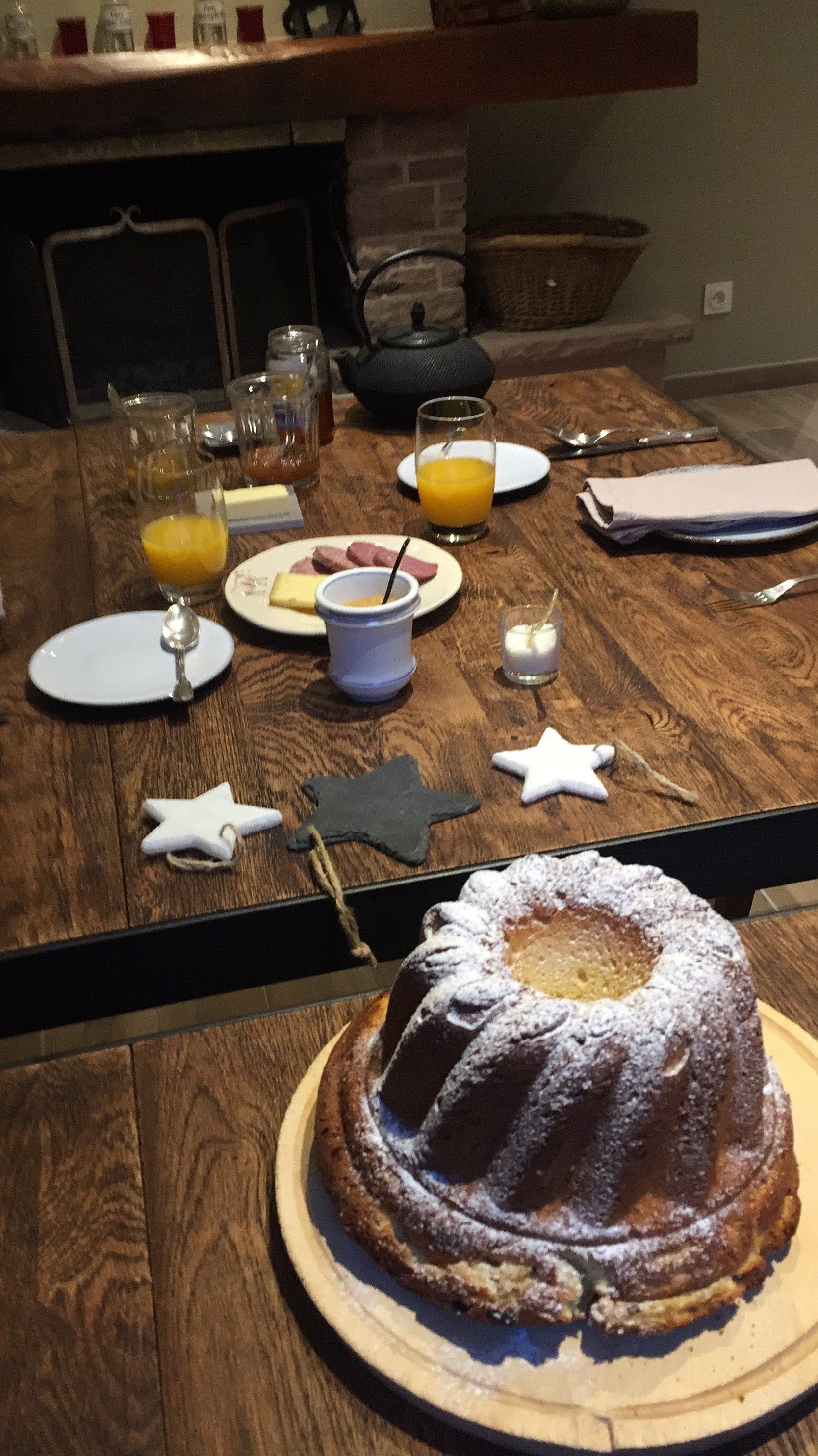 A wooden dining table with plates, glasses, and a bundt cake.
